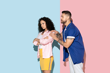 Image showing Young emotional man and woman on pink and blue background