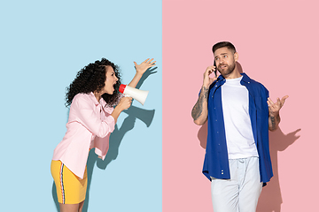 Image showing Young emotional man and woman on pink and blue background