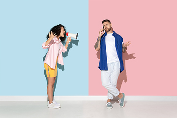 Image showing Young emotional man and woman on pink and blue background