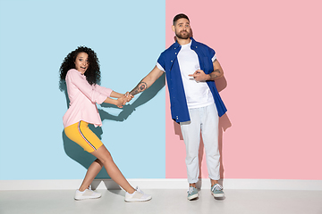 Image showing Young emotional man and woman on pink and blue background