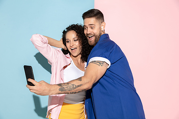 Image showing Young emotional man and woman on pink and blue background