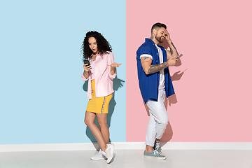 Image showing Young emotional man and woman on pink and blue background