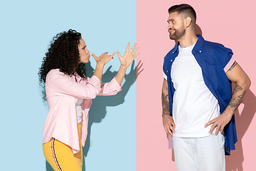 Image showing Young emotional man and woman on pink and blue background