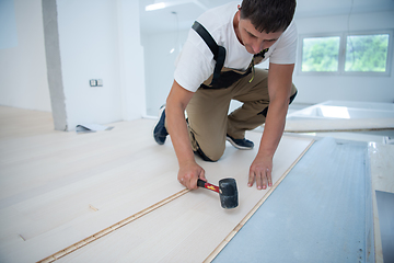 Image showing Professional Worker Installing New Laminated Wooden Floor