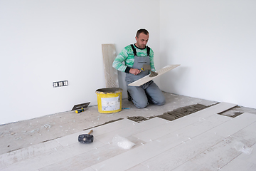 Image showing worker installing the ceramic wood effect tiles on the floor