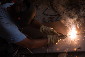 Image showing welder with protective mask welding steel