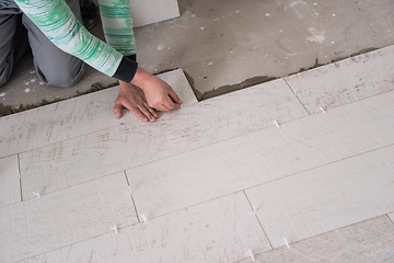 Image showing worker installing the ceramic wood effect tiles on the floor