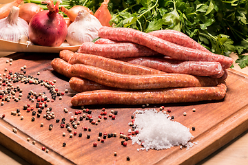 Image showing raw sausages with chilli and herbs on a wooden board with spices