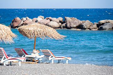 Image showing beach with umbrellas and deck chairs by the sea in Santorini