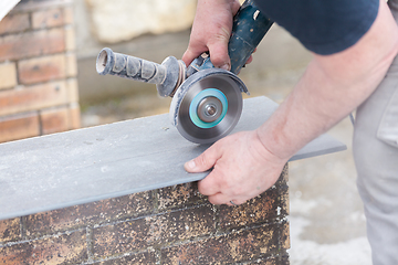 Image showing tiler cutting a tile with a grinder