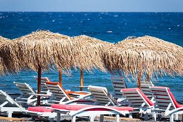 Image showing beach with umbrellas and deck chairs by the sea in Santorini