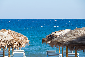 Image showing beach with umbrellas and deck chairs by the sea in Santorini