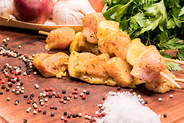 Image showing raw chicken skewers marinated with lemon on a wooden board