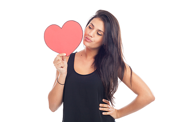 Image showing beautiful happy brunette woman holding and showing a big red hea