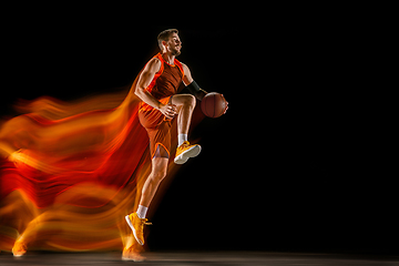 Image showing Young caucasian basketball player against dark background in mixed light