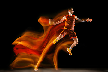 Image showing Young caucasian basketball player against dark background in mixed light