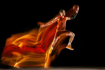 Image showing Young caucasian basketball player against dark background in mixed light