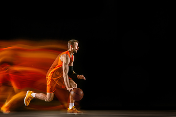 Image showing Young caucasian basketball player against dark background in mixed light