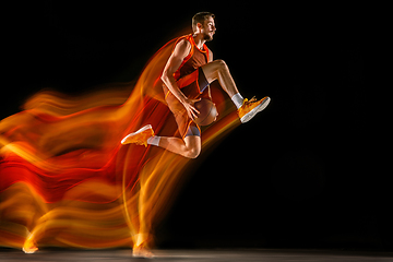 Image showing Young caucasian basketball player against dark background in mixed light