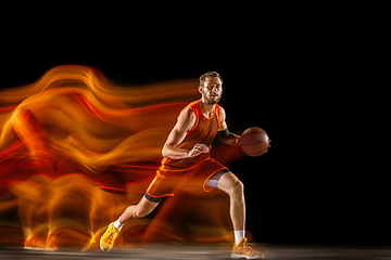 Image showing Young caucasian basketball player against dark background in mixed light