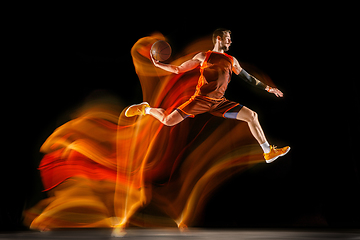 Image showing Young caucasian basketball player against dark background in mixed light