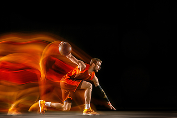 Image showing Young caucasian basketball player against dark background in mixed light