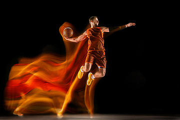 Image showing Young caucasian basketball player against dark background in mixed light