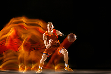 Image showing Young caucasian basketball player against dark background in mixed light