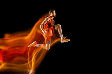 Image showing Young caucasian basketball player against dark background in mixed light