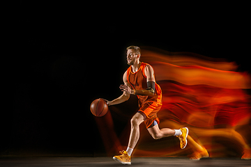 Image showing Young caucasian basketball player against dark background in mixed light