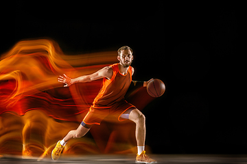 Image showing Young caucasian basketball player against dark background in mixed light