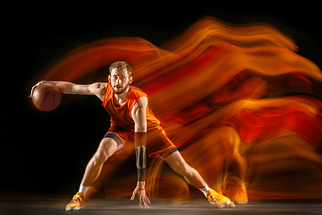 Image showing Young caucasian basketball player against dark background in mixed light