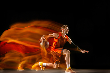 Image showing Young caucasian basketball player against dark background in mixed light