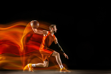 Image showing Young caucasian basketball player against dark background in mixed light