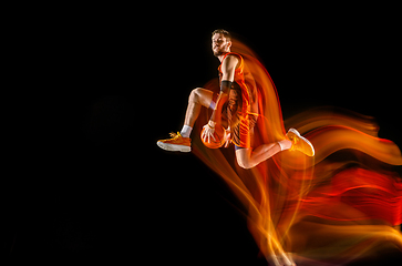 Image showing Young caucasian basketball player against dark background in mixed light