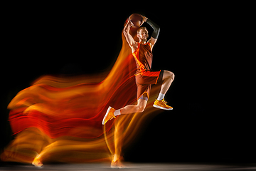 Image showing Young caucasian basketball player against dark background in mixed light