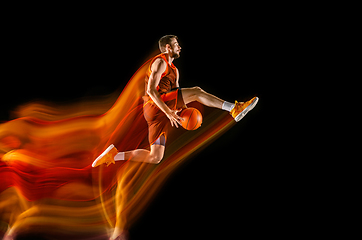 Image showing Young caucasian basketball player against dark background in mixed light