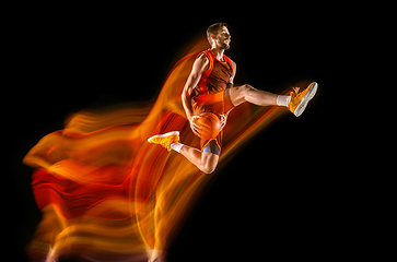 Image showing Young caucasian basketball player against dark background in mixed light