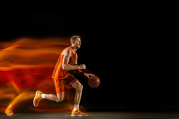 Image showing Young caucasian basketball player against dark background in mixed light