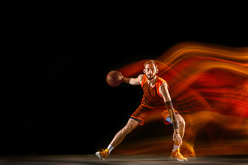 Image showing Young caucasian basketball player against dark background in mixed light