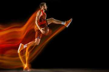 Image showing Young caucasian basketball player against dark background in mixed light