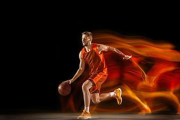 Image showing Young caucasian basketball player against dark background in mixed light