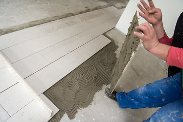 Image showing worker installing the ceramic wood effect tiles on the floor