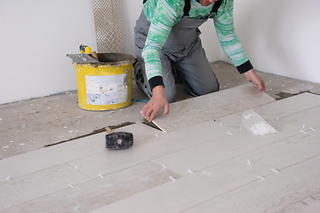 Image showing worker installing the ceramic wood effect tiles on the floor