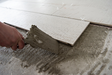 Image showing worker installing the ceramic wood effect tiles on the floor