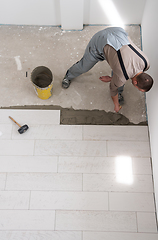 Image showing worker installing the ceramic wood effect tiles on the floor