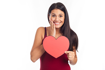 Image showing beautiful happy brunette woman holding and showing a big red hea