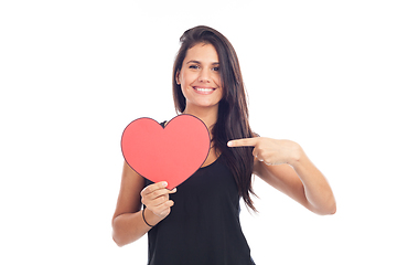 Image showing beautiful happy brunette woman holding and showing a big red hea