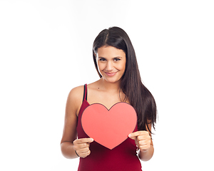 Image showing beautiful happy brunette woman holding and showing a big red hea