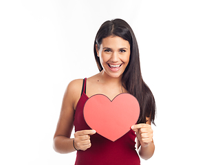 Image showing beautiful happy brunette woman holding and showing a big red hea